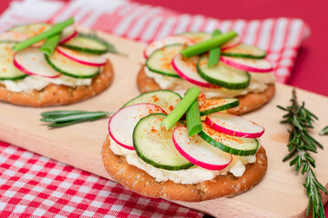 Light Breakfast or Diet Eating - Crispy Cracker Sandwich with Cream Cheese, Fresh Cucumber, Green Onions and Radish on Wooden Cooking Board on Magenta Background