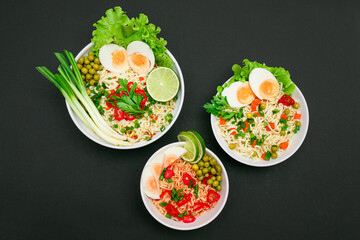 Beautiful Noodle Dish with Green Onions, Eggs, Green Pea, Red Hot Pepper, Greens and Lime on Sushi Mat. Instant Noodles with Vegetables