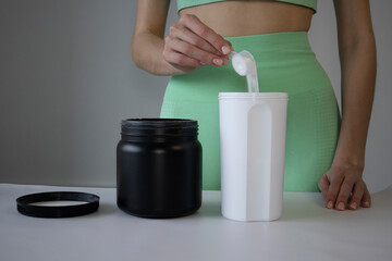 Close up of women with measuring scoop of whey protein and shaker bottle, preparing protein shake....