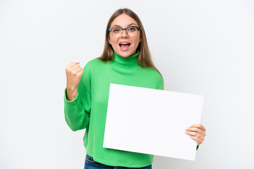 Young caucasian woman isolated on white background holding an empty placard and celebrating a victory