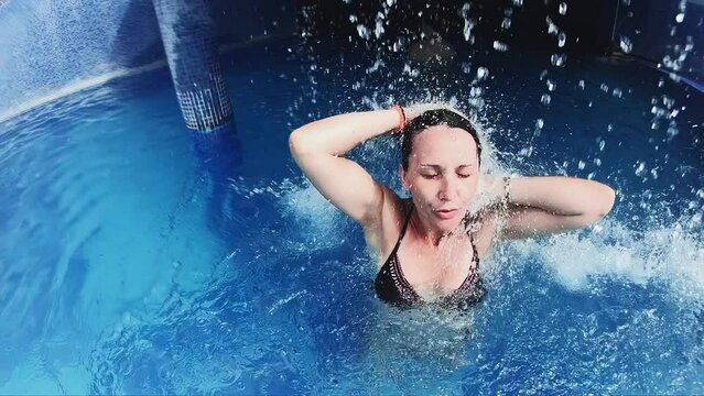 Woman hydrotherapy relaxing under water jet stream in spa resort
