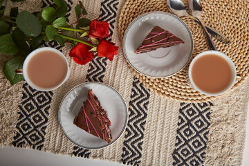 Festive breakfast with cherry chocolate cake pieces, coffee cups, red roses and St Valentines day, aesthetic flat lay