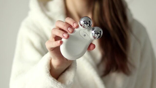 Microcurrent device. for massage of a woman's face in her hands, selective focus, close-up.