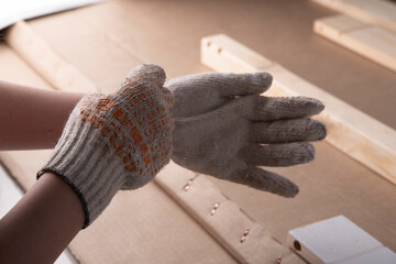 Painter, builder, the master puts on gloves. Painting of construction wooden parts with white paint