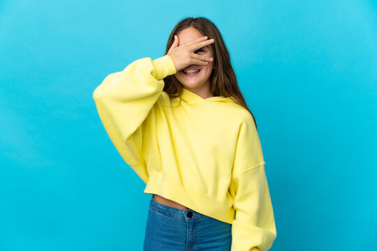 Little Girl Over Isolated Blue Background Covering Eyes By Hands And Smiling