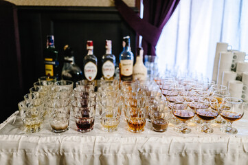 Spirits tasting. A lot of drinks in glass bottles and glasses on the festive table. Composition of assorted alcoholic beverages.