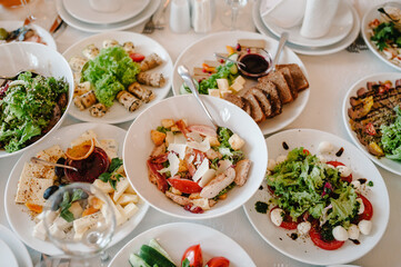 Serves dinner on a festive table. Food, Salads, Meat, Fish Meals. Festive table at wedding banquet. Decor. Details. Top view.