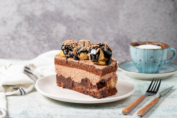Chocolate and profiteroles cake. Layered cake with chocolate and cream on plate on stone background. close up