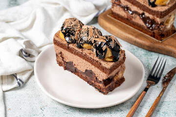 Chocolate and profiteroles cake. Layered cake with chocolate and cream on plate on stone background. close up