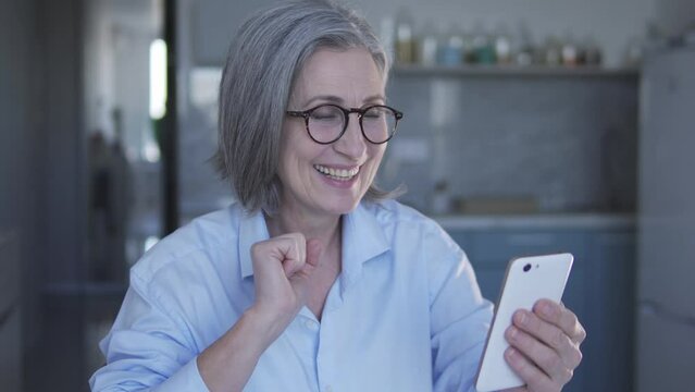 Happy positive woman turning on video with music on smartphone and dancing, having fun and moving to the rhythm, spending time on internet, looking through web-pages in social networks