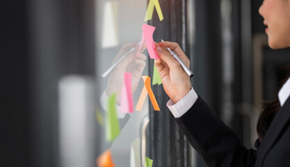 Creative businesswoman writing on sticky notes on a glass wall