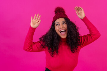 Portrait curly-haired woman in a wool hat on a pink background having fun, studio shot