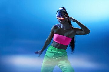 Mixed race female dancing in studio with blue neon illumination