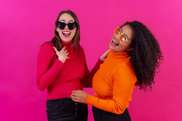 Female friends in sunglasses having fun pink background, studio shot