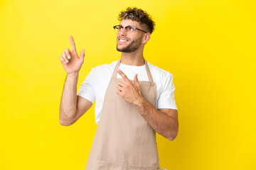 Restaurant waiter blonde man isolated on yellow background pointing with the index finger a great...