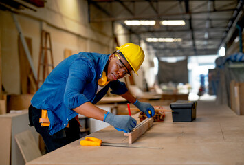 African American carpenter man use pencil to mark on timber during work with in wood factory workplace.