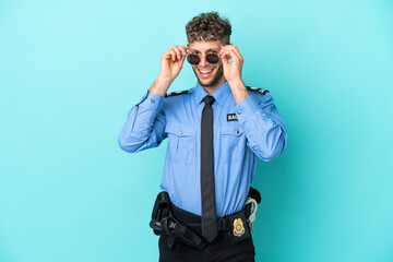 Young police blonde man isolated white on blue background with glasses and surprised