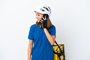 Young caucasian woman with thermal backpack isolated on white background keeping a conversation with the mobile phone with someone