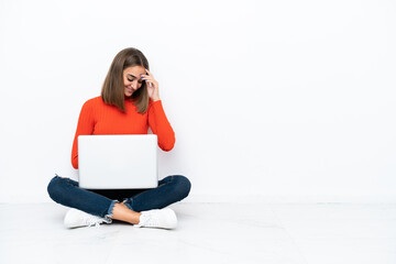 Young caucasian woman sitting on the floor with a laptop laughing