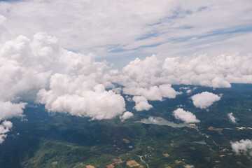 Aerial view from the top view of the forest, mountain, meadow and abundant plantation fields on summer, covered by white fluffy cloud