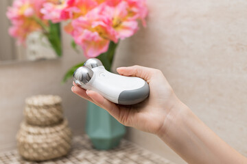 female hand holding microcurrent facial toning device. Modern beauty skin care concept. selective...