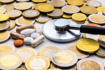 Medicines, with stethoscope and coins around. Costs of medicines, medical therapies and health. Pharmaceutical price increases.
