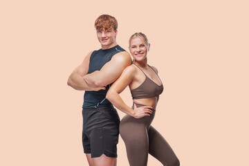  Sporty young couple posing on pastel background.