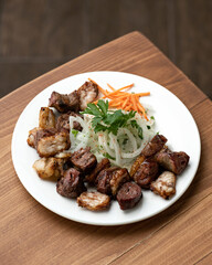 Grilled sliced sausages on plate with salad on wooden table. Soft focus. Serving meals. View from above. Photo for menu. 
