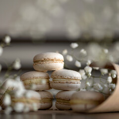 Fototapeta na wymiar Macaroni. French dessert. Cream colored macarons on paper. Decorated with dried flowers. Blurred background. Close-up. 