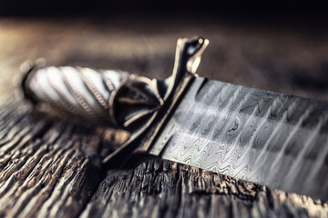Handmade antique dagger with Damascus steel on old oak table