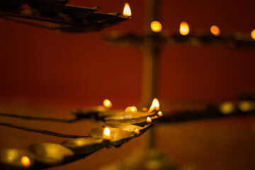 oil lamps lit with yellow flames during hindu puja rituals. multiple heads of lamps made with brass.