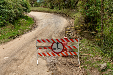 barrier with a no entry sign on a dirt road, detour - written in Spanish on the sign