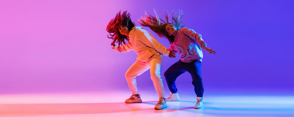 Music. Young expressive hip-hop dancers dancing in neon. Concept of dance, youth, hobby, dynamics, movement, action, ad. Banner - obrazy, fototapety, plakaty