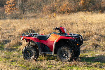 Red quad bike in the autumn field.