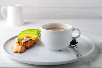 Coffee with cream and cream cheese sandwich with avocado