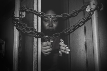 Black and white photo helpless African American woman trapped in an illicit container locked with a...