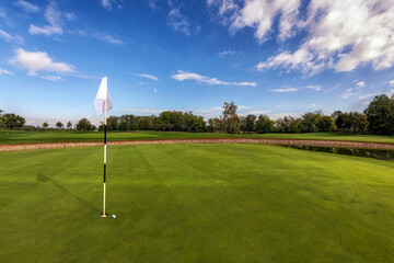 Golf course putting green under blue cloudy sky