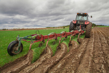 Plowing, ploughing  in the fields on a dark cloudy spring day.  Agricultural machinery, plow, plough.