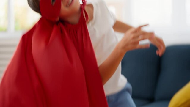 Schoolboy having fun wearing superhero costume, playing at home, leisure time