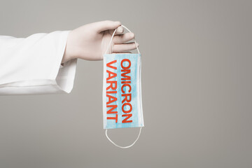 Cropped view of scientist in latex glove holding medical mask with omicron variant lettering...