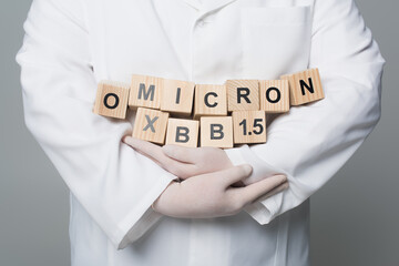 Cropped view of scientist in latex gloves holding wooden cubes with omicron xbb lettering isolated...