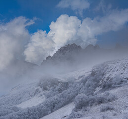 snowbound mountain valley in mist and dense clouds, seasonal mountain travel scene