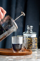Thai anchan blue tea is poured from the kettle into a transparent glass.
