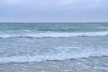 Fototapeta na wymiar Rolling waves on sandy beach Baltic Sea.