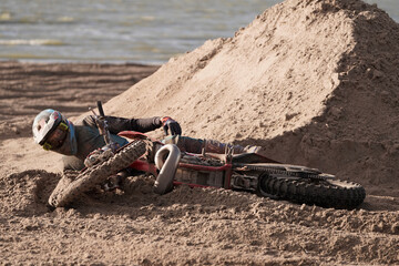Motocross Rennen am Strand. Motorrad mit Fahrer liegt im Sand
