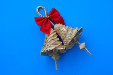 Bell made out of straw on a blue background.