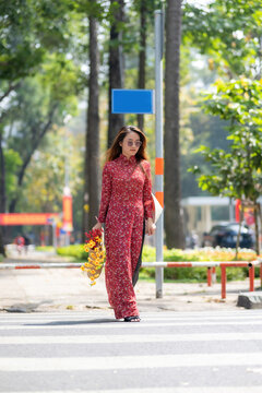 Vietnamese girl with Ao Dai dress walking on street, Ho Chi Minh city, Vietnam. Ao dai is famous traditional costume for woman in Vietnam. Tet holiday and New Year.
