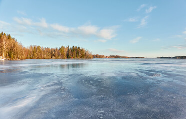 Obraz premium Panoramic view of the forest lake on a sunny winter day. Evergreen trees. Soft sunlight. Frozen water surface. Finland. Environment, nature, ecology, ecotourism, cold weather, climate change themes
