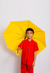 little boy fashion A smiling child holding a yellow umbrella in a red Chinese dress. Chinese New Year, Chinese New Year