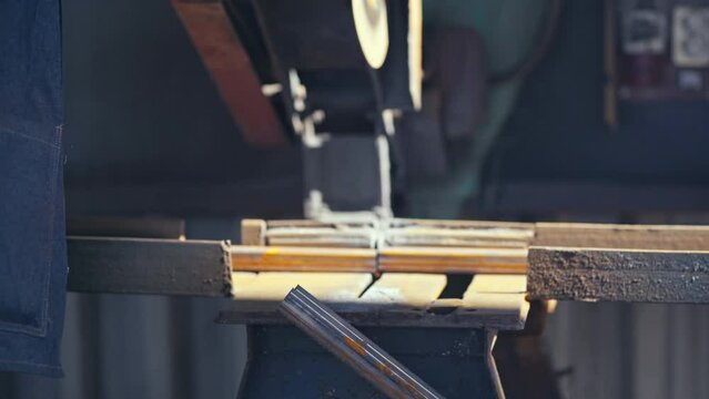 Male hand cuts off pieces of water pipe with angle grinder. Cutting of a steel with splashes of sparks at construction site. Sparks during cutting of metal angle grinder